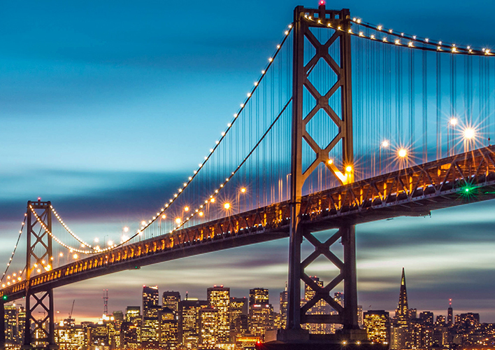 Golden gate bridge at night with a city line.